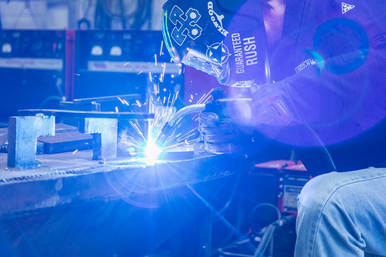 welder welding with helmet and blue sparks