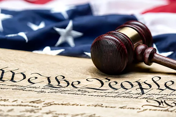Image of the constitution with gavil setting on it and American Flag in background