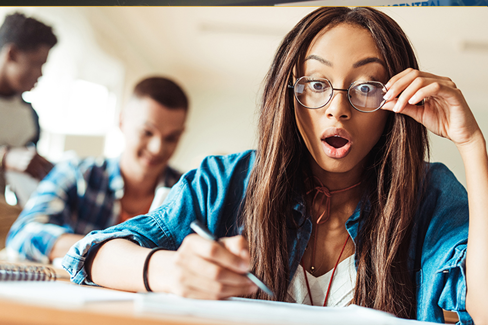 girl with glasses at her desk looking surprised